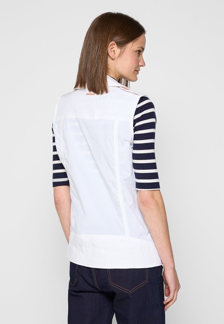 Camicetta bianca senza maniche con maniche a righe contrastanti blu e bianche, presenta un collo rotondo e una texture liscia. La vista posteriore mostra i dettagli delle cuciture.