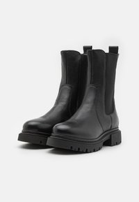 Botas de couro pretas até ao tornozelo apresentam painéis laterais elásticos, bicos arredondados e uma sola robusta e texturada para maior tração e durabilidade.