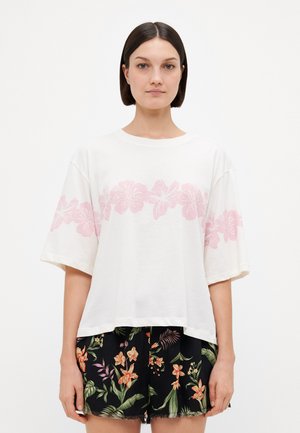 White short-sleeve t-shirt with pink floral print across the chest, paired with black shorts featuring a colorful floral pattern and frayed hem.