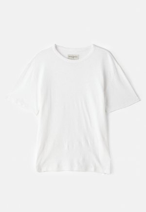 T-shirt en coton blanc avec un col rond, des manches courtes et une coupe décontractée. Présente une finition texturée. Étiquette visible à l'intérieur du col.