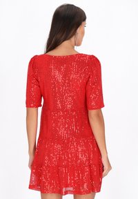 Rochie roșie din paiete cu mâneci scurte, design în straturi, țesătură texturată și decolteu rotund, care prezintă un model vibrant și strălucitor.
