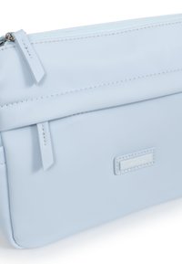 Borsa sintetica azzurro chiaro con finitura liscia, dotata di una cerniera superiore e di un'etichetta del marchio visibile. Include cuciture decorative e linguette.