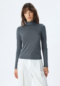 Dunkelgraues Langarm-Turtleneck-Shirt aus einem glatten, elastischen Material, das eine enganliegende Passform und minimale Nahtdetails aufweist.