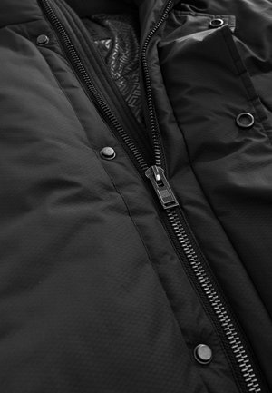 Schwarze isolierte Jacke mit vollem Reißverschluss, Druckknöpfen und einem geometrisch gemusterten Futter. Glatte Außenseite mit matter Oberfläche.