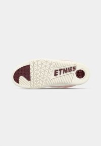 Sole tenisky Etnies v béžové barvě s texturovaným vzorkem. Obsahuje vínový akcent a logo, se vzorovaným designem pro lepší grip.