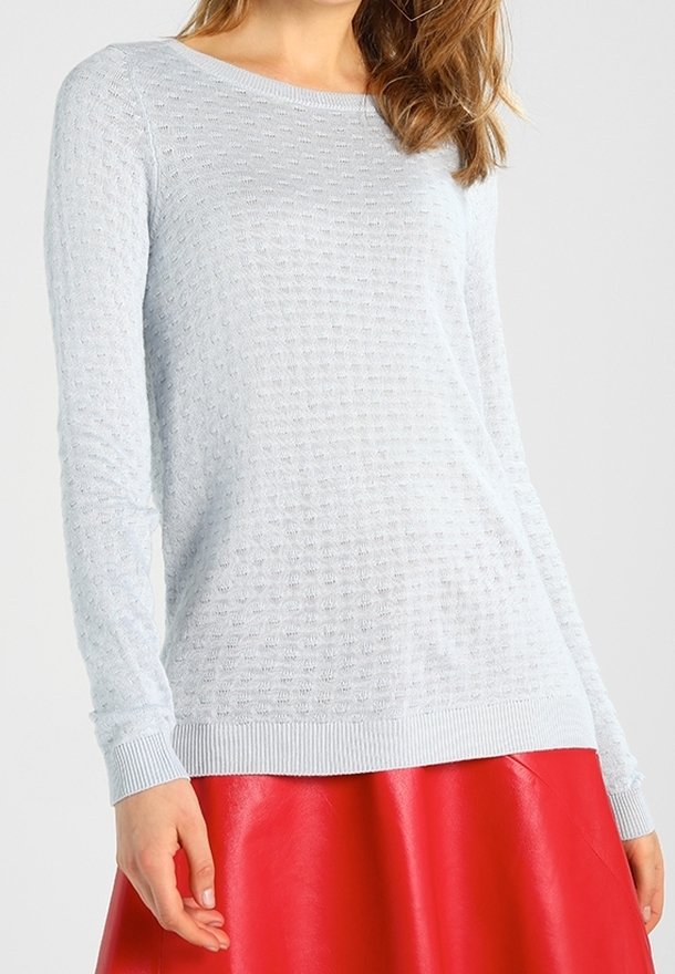 Suéter de punto azul claro con un patrón texturizado, mangas largas y puños de canalé, combinado con una falda corta de piel roja brillante.
