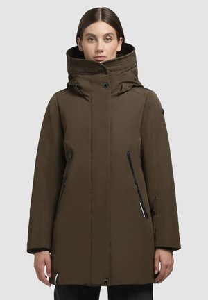 Parka impermeabile verde oliva con colletto alto, dotata di tasche con zip nere, chiusura frontale con bottoni e una superficie liscia e opaca.