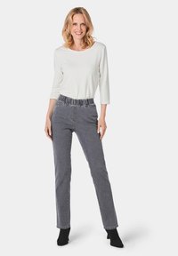 Witte lange mouw top; grijze stoffen broek met elastische tailleband; slim fit, taps toelopende pijpen; enkel lengte, subtiel textuurpatroon.