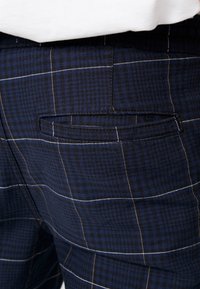 Námořnické kárované kalhoty z tkané látky; mají jednu zadní kapsu s elegantním designem a kontrastními oranžovými švy.