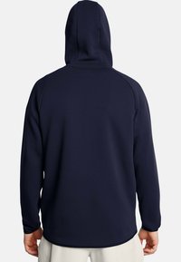 Marineblaue Kapuze mit langen Raglanärmeln, glatter Textur und abgerundetem Saum, ohne sichtbare Logos oder Verzierungen auf der Rückseite.