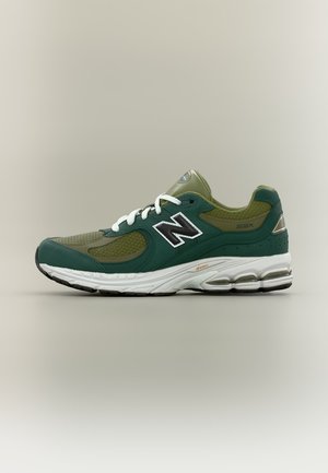 Πράσινο και ελιά New Balance 2002R αθλητικό παπούτσι με λευκά κορδόνια και μαλακή λευκή σόλα, εμφανίζεται από την πλευρά σε ουδέτερο φόντο.