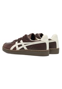 Low-top sneakers in dark brown with white stripes and heel panel, brown laces, and rubber soles on a white background.