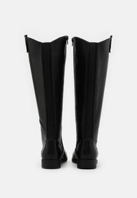 Black knee-high boots made of smooth leather with a raised seam and elastic inserts at the back, featuring a sleek rounded toe and low heel.