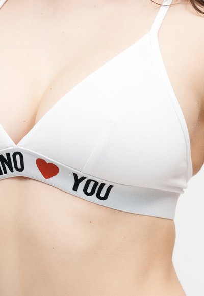 Λευκό μπουστάκι με μαύρο κείμενο "NO" και "YOU" διαχωρισμένα με κόκκινη καρδιά στη λωρίδα, φορεμένο από άτομο με ανοιχτόχρωμο δέρμα.