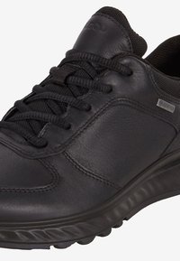 Sneaker nera in pelle con superficie texturizzata, chiusura con lacci, colletto imbottito e suola in gomma con un logo discreto e dettagli Gore-Tex.