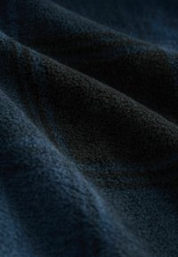 Tmavomodrá textúrovaná tkanina s mäkkým, chlpovým povrchom, s jemnými variáciami odtieňa a hĺbky po celej materiáli.