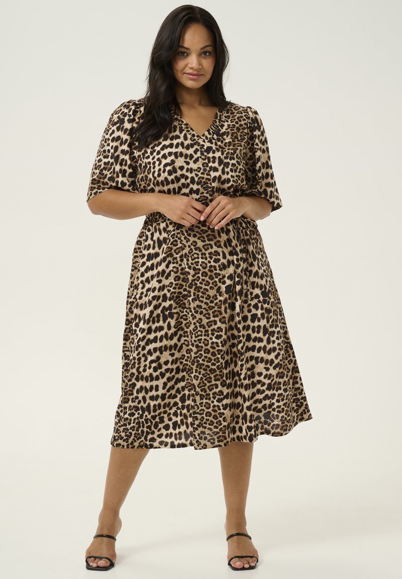 Robe midi imprimée léopard avec des manches courtes, décolleté en V, taille froncée et jupe flottante. Le tissu a une texture lisse et douce.