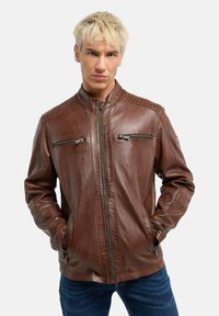 Braune Lederjacke mit Stehkragen, gesteppten Schulterakzenten, zwei seitlichen Reißverschlusstaschen und einem Reißverschluss vorne.