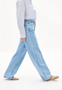 Ljust blå vida jeans i denim med sidofickor, bälteshällor och rak skärning, tillsammans med en ljus knäppskjorta.