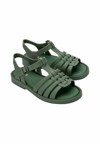 Zielone gumowe sandały z plecionym paskiem, otwarty palec i regulowany pasek na kostce. Strukturalna podeszwa z detalem w zygzak.