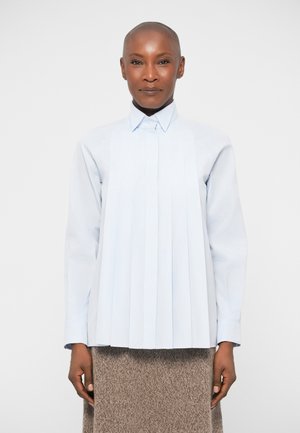 Svijetloplava košulja na dugih rukava s vertikalnim nabora, s kragnom. Mekana tkanina, strukturirani dizajn, uparen s teksturiranom smeškastom suknjom.