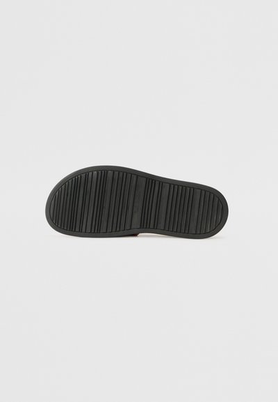 Schwarze Gummisohle mit strukturiertem Profil für guten Halt. Abgerundete Form mit leichtem Bogen an der Zehenspitze. Minimalistisches Design, ohne sichtbare Marken. 