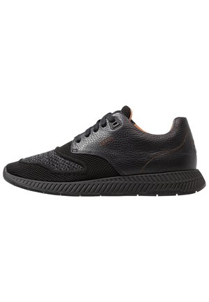 Schwarzer flacher Sneaker mit strukturiertem Leder- und Mesh-Obermaterial, Schnürverschluss und dicker profilierter Gummisohle.
