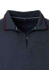 Mørkeblå pullover med lynlås-kra, struktureret stof og kontrasterende røde og hvide striber i kraven. Brandmærket er synligt indeni.