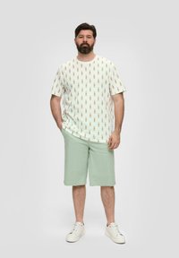 Witte t-shirt met een ananasprint, gecombineerd met lichtgroene shorts. Beide items zijn casual en gemaakt van zachte, lichte stof.