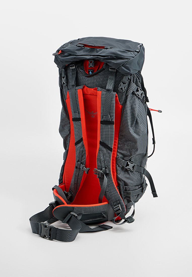 Rugzak van duurzaam zwart en grijs stof met een rasterpatroon, rode gevoerde binnenzijde, verstelbare schouderbanden en meerdere bevestigingspunten.