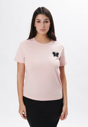 Kurzärmliges, pinkes Baumwoll-T-Shirt mit einem schwarzen, mit Pailletten besetzten Schmetterlingsapplikation auf der linken Brust. Glatte Textur und runder Ausschnitt.