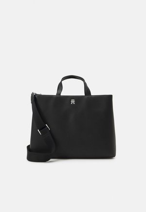 Black leather tote bag with dual handles, a removable shoulder strap, glossy silver logo, smooth texture, and structured shape.