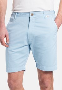 Lichtblauwe shorts van ademend materiaal, met een knoopsluiting, zijzakken en een rechte snit die boven de knie eindigt.
