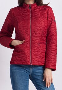 Veste matelassée rouge avec un col montant, fermeture éclair sur toute la longueur et un motif texturé. Elle possède des poches latérales et un design ajusté.