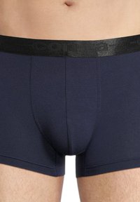 Navy blue boxer briefs made of soft fabric, featuring a black elastic waistband with branding. Smooth texture and fitted design.