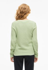 Πράσινο πλεκτό πουλόβερ με υφή, μακριά μανίκια, στρογγυλή λαιμόκοψη και εφαρμοστό τελείωμα, εμφανιζόμενο από πίσω σε λευκό φόντο.