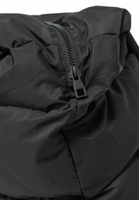 Crna puffer jakna s detaljima koji uključuju vidljivi zip i nabranog materijala, prikazuje glatku teksturu i čvrsto pakiranu izolaciju.
