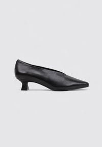 Zapato de tacón negro de cuero con punta afilada y tacón bajo de forma cuadrada. Textura suave y diseño elegante con un perfil minimalista.