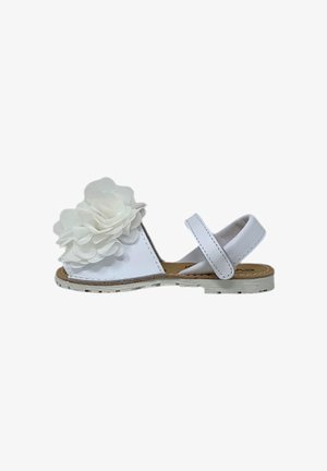 Sandal bianca con due fasce regolabili, caratterizzata da un grande fiore bianco sulla zona delle dita. Suola piatta e semplice dettaglio di cucitura.