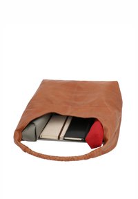 Sac en cuir marron posé ouvert montrant le contenu comprenant une pochette grise, un carnet beige avec une lanière, un livre noir et un parapluie rouge.