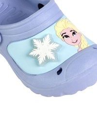 Scarpa croc in un delicato colore viola chiaro con un pannello blu che presenta un design di fiocchi di neve e un'illustrazione di un personaggio. Realizzata in morbido materiale plastico.