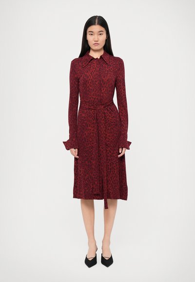 Robe à motif léopard rouge avec un col, des manches longues à volants, une taille ceinturée, et une longueur jusqu'au genou.