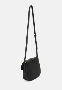 Sac en bandoulière en cuir noir avec une longue sangle réglable et un rabat à fermeture, présenté sur fond blanc uni.