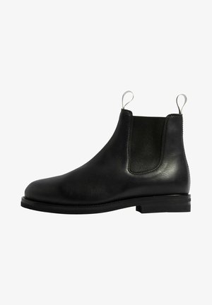 Stivale Chelsea in pelle nera con pannelli laterali elasticizzati, punta tonda e suola piatta in gomma. Include linguette per una facile calzata.