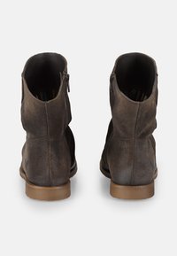 Botas de tobillo de ante marrón con un tacón bajo, que cuentan con una cremallera lateral y un detalle de costura sutil, mostrando un acabado texturizado.