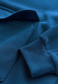 Blauw sweatshirt met een textuurstof, opgevouwen kraag en geribbelde boorden. Glad oppervlak met nette naden en een diepblauwe tint.