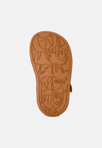 Ruskea kumipohja, jossa on leikkisä eläinten kohokuviointi, 'CAMPER' -logo ja teksturoidut urat pidon parantamiseksi.