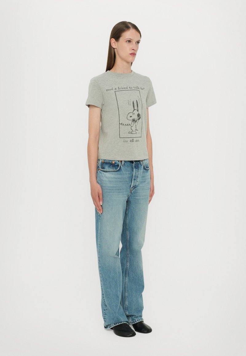 Gray cropped t-shirt featuring a black graphic print of a cartoon character. Paired with light blue wide-leg jeans and black shoes.