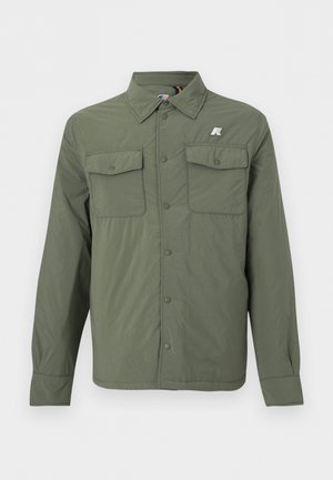 Chaqueta camisa de manga larga color verde oliva con bolsillos en el pecho con solapa y botón, y un pequeño logo en la parte superior del pecho izquierdo.