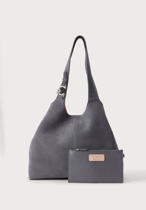 Borsa in camoscio grigio scuro con una tracolla larga e fibbia argento, accompagnata da un portafoglio in pelle grigio scuro con zip e etichetta beige del marchio.